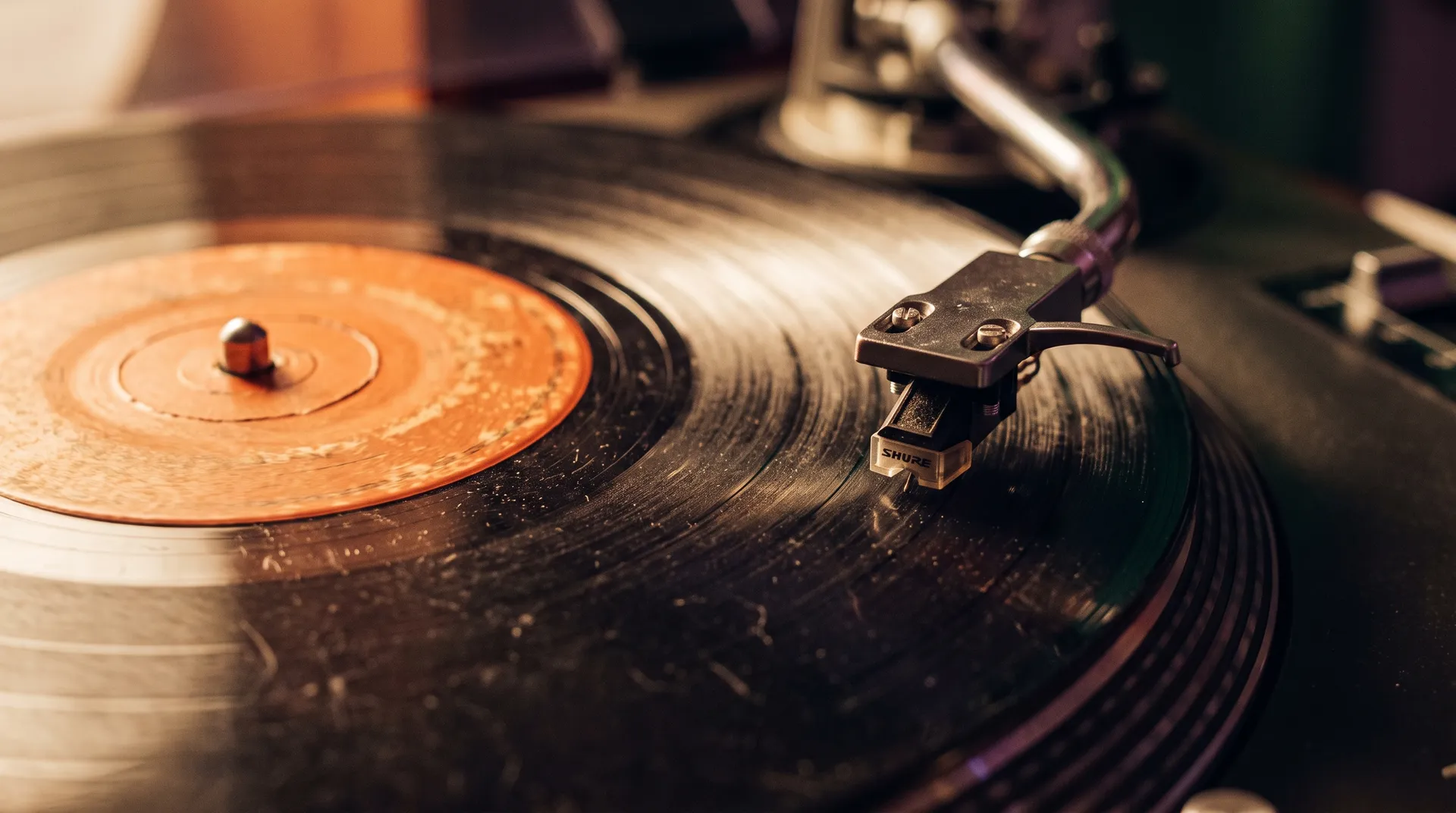 A 45 rpm single with a worn orange label spinning on a turntable, the needle riding the groove